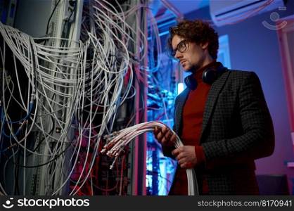 IT man with bunch of cables in hands while working at network server room. Engineer setting farm of mining cryptocurrency. IT man with bunch of cables in hands in server room