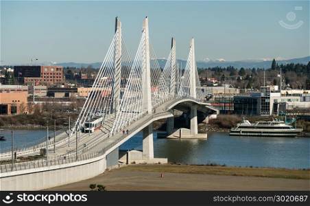 It&rsquo;s a clear day in Portland Oregon at Tilikum Crossing as people traverse the river with the Cascade Mountain Range