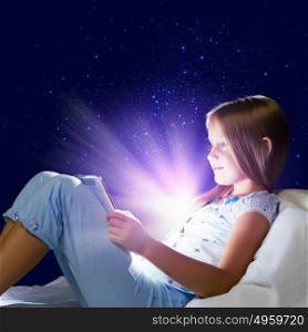 It&rsquo;s bedtime. Girl sitting in bed and playing with tablet pc