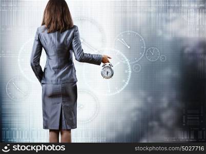 It&rsquo;s time. Rear view of businesswoman holding alarm clock in hand