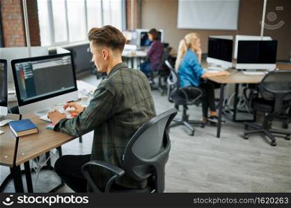 IT specialists group works at the tables in office. Web programmer or designer at workplace, creative occupation. Modern information technology, corporate team. IT specialists group works at the tables in office