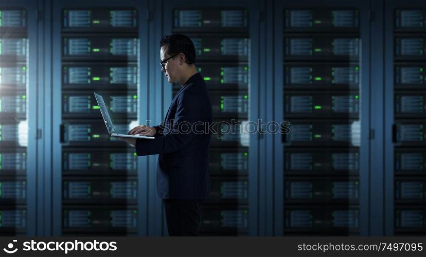 IT Technician in suit works on laptop working in server room .
