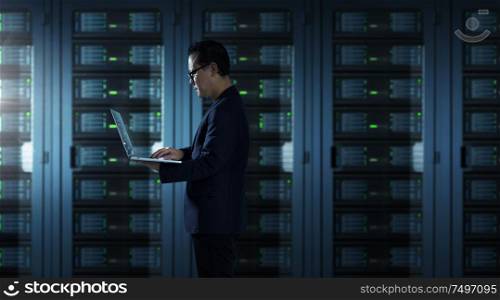 IT Technician in suit works on laptop working in server room .