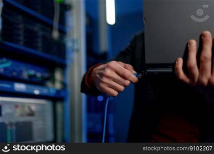 IT technician switching wire to laptop computer. Closeup view. Data center, system administration concept. IT technician switching wire to laptop computer closeup