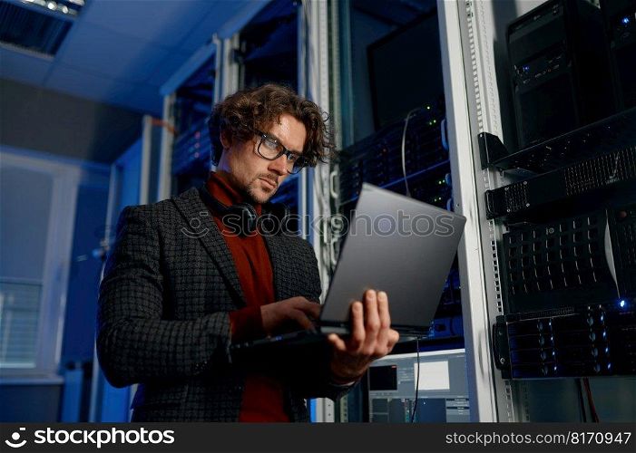 IT technician using digital tablet while working in data center with server rack. Smart technology system administration. IT technician using digital tablet while working in data center with server rack