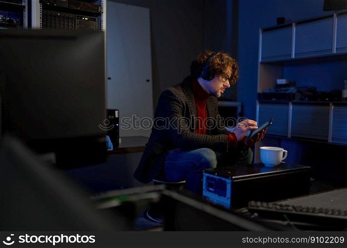 IT technician using digital tablet while working with essential equipment in data center. IT professional taking coffee break. IT technician using digital tablet while working in data center