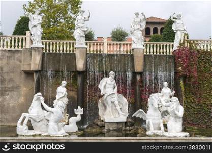 itailian garden with sculptures and waterfall with plants growing on the background