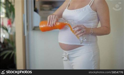 italian 6 months pregnant woman drinking orange juice and looking at camera