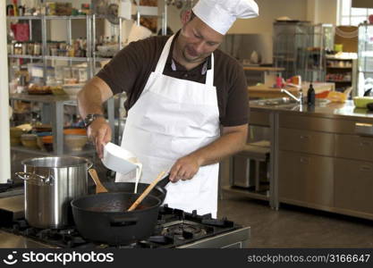 Italian chef adding some cream into the pasta sauce