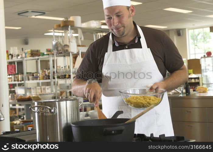 Italian chef stirring the sauce and ready to add the pasta