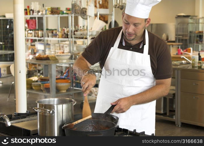 Italian chef working in the kitchen stirring the mushrooms