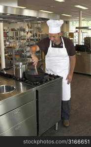 Italian chef working in the kitchen, stirring the tomatoe sauce