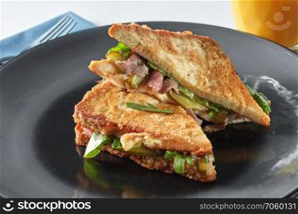 Italian ciabatta sandwich with parma ham and herbs on black plate. Italian ciabatta sandwich with parma ham and herbs