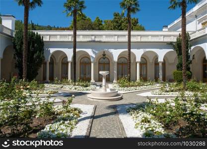Italian courtyard in the Livadia Palace with palm trees and a fountain in the middle on a sunny day, Crimea.