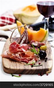 Italian cuisine. Antipasto. Prosciutto, melon, salami, olives and wine