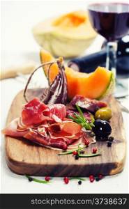 Italian cuisine. Antipasto. Prosciutto, melon, salami, olives and wine