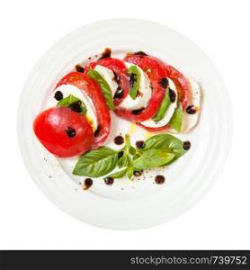 italian cuisine insalata caprese (caprese salad) - top view of sliced mozzarella cheese and tomato with basil leaves seasoned by olive oil and balsamic vinegar on plate isolated on white background