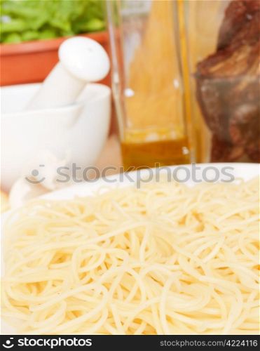 Italian Cuisine - spaghetti, dried tomatoes, garlic, basil, mortar with pestle and olive oil