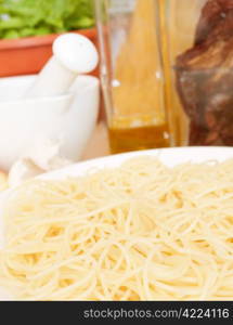 Italian Cuisine - spaghetti, dried tomatoes, garlic, basil, mortar with pestle and olive oil