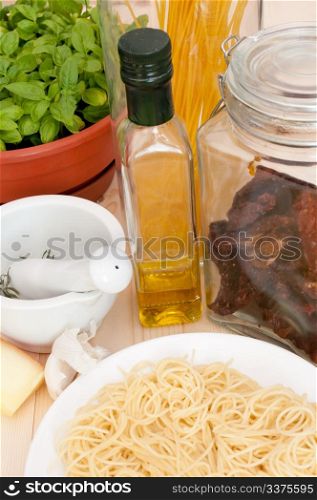 Italian Cuisine - spaghetti, dried tomatoes, pecorino cheese, basil, garlic, mortar with pestle and olive oil
