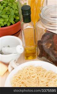 Italian Cuisine - spaghetti, dried tomatoes, pecorino cheese, basil, garlic, mortar with pestle and olive oil