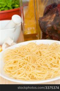 Italian Cuisine - spaghetti, dried tomatoes, pecorino cheese, garlic, basil, mortar with pestle and olive oil