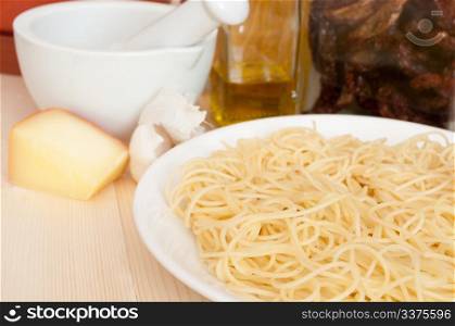 Italian Cuisine - spaghetti, dried tomatoes, pecorino cheese, garlic, mortar with pestle and olive oil