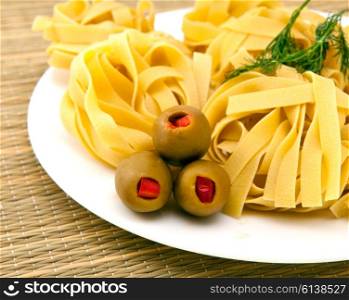 Italian fettuccine nest pasta with olives on a plate