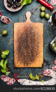 Italian food and antipasti around old wooden cutting board, top view. Italian food background for menu or coking recipes, frame