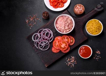 Italian food background. Ingredients on dark background. Cooking background. Raw ingredients for delicious Italian pasta  tomatoes, minced meat, pasta, spices and herbs