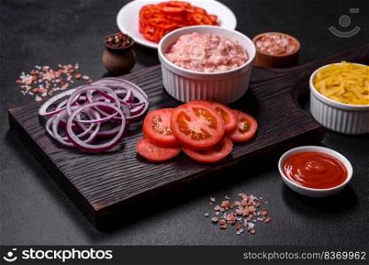 Italian food background. Ingredients on dark background. Cooking background. Raw ingredients for delicious Italian pasta  tomatoes, minced meat, pasta, spices and herbs