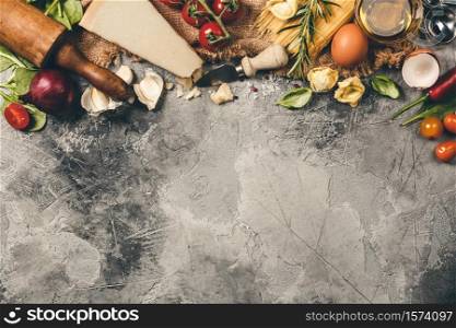 Italian food background with vine tomatoes, basil, spaghetti, spinach, onion, parmesan, olive oil, garlic, peppercorns rosemary and eggs Slate background. Italian food background. Slate background with space for text