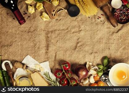 Italian food background with vine tomatoes, basil, spaghetti, spinach, onion, parmesan, olive oil, garlic, peppercorns, rosemary and eggs. Burlap background