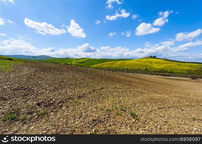 Italian landscape with meadows early in the spring. Agriculture in Italy, plowed fields, pastures and farmhouse on the hill.. Plowed fields, pastures and farmhouse