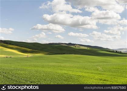 Italian landscape with meadows early in the spring. Agriculture in Italy, fields, pastures and farmhouses on the hill.. Fields, pastures and farmhouse