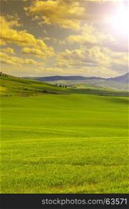 Italian landscape with meadows early in the spring at sunrise. Agriculture in Italy, fields, pastures and farmhouses on the hill.