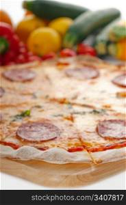 Italian original thin crust pepperoni pizza with fresh vegetables on background