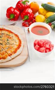 Italian original thin crust pizza Margherita with gazpacho soup and watermelon on side,and vegetables on background