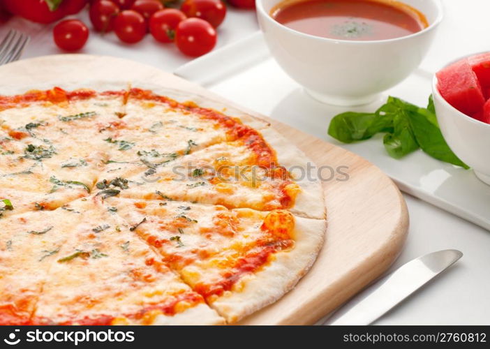 Italian original thin crust pizza Margherita with gazpacho soup and watermelon on side,and vegetables on background