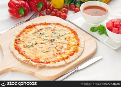 Italian original thin crust pizza Margherita with gazpacho soup and watermelon on side,and vegetables on background