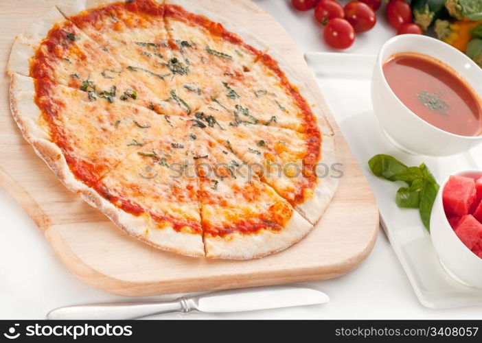 Italian original thin crust pizza Margherita with gazpacho soup and watermelon on side,and vegetables on background