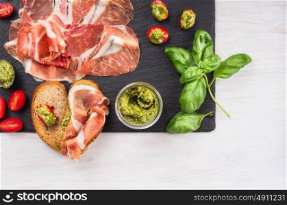 italian parma ham with basil pesto, tomatoes and bread, top view