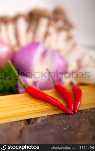 Italian pasta and mushroom sauce raw ingredients over rustic old wood