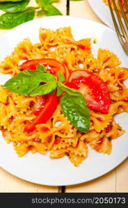 Italian pasta farfalle butterfly bow-tie with tomato basil sauce over white rustic wood table