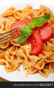 Italian pasta farfalle butterfly bow-tie with tomato basil sauce over white rustic wood table