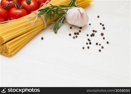Italian pasta ingredients on white wooden table, tomatoes, garlic, rosemary, pepper, macro copy space. Italian pasta ingredients on white wooden table, macro
