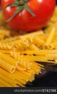 Italian pasta selection with fresh tomato over black closeup DOF