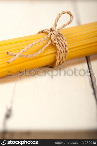 Italian pasta spaghetti tied with a rope on a rustic table