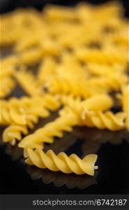 Italian pasta spiral fusilli over black closeup DOF