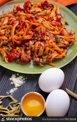 italian pasta with tomatos and herbs on dark wooden table. italian pasta recipe.